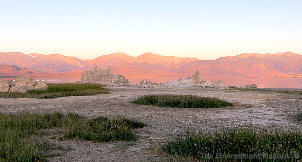 Morning sunlight hitting the east face of the Sierra Nevada with Mono Lake tufa and rounds of marsh grass in the foreground